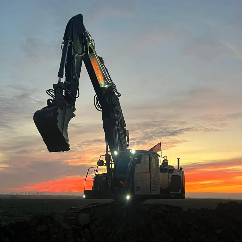 Schwarzer Bagger mit rotem ER vor dem Abendhimmel